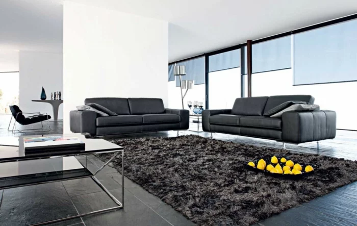 moderner Wohnbereich mit grauen Wohnzimmer Fliesen und schwarzen Sofas