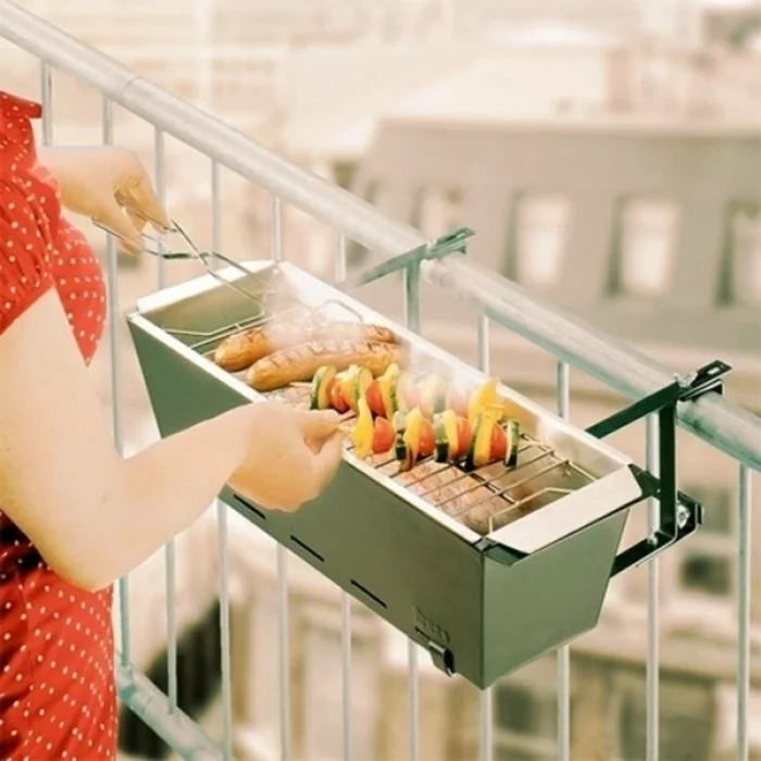 Frau grillt auf dem Balkon auf einem kleinen Grill