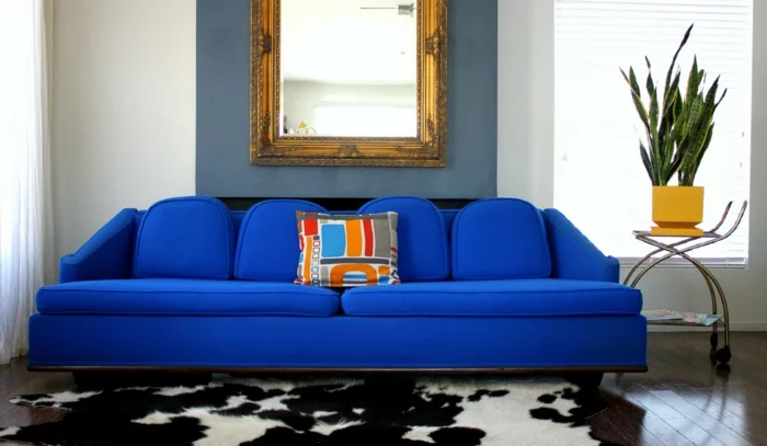 blaues Sofa, schwarz-weißer Teppich und Wandspiegel