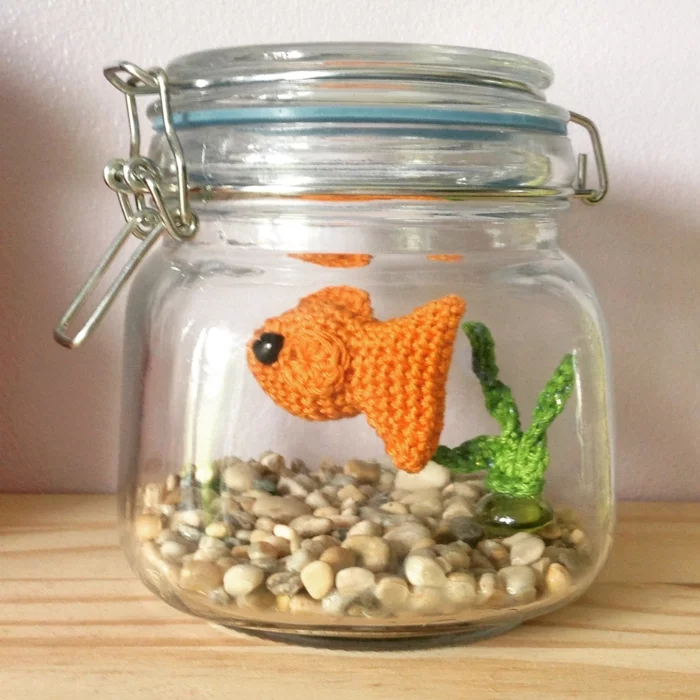 Amigurumi-Fisch in Orange in einem Einmachglas mit Dekosteinen 