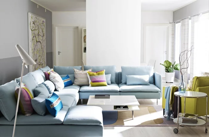 blaues Sofa in einem hellen Farbton und viele farbige Dekokissen