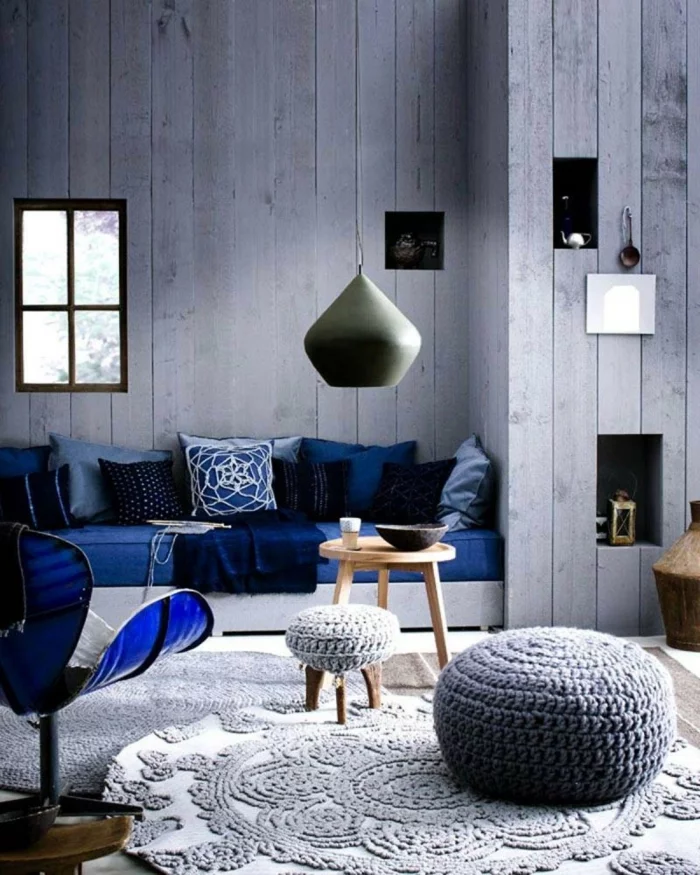 graues Wanddesign in Holzoptik und Sofa in Blau