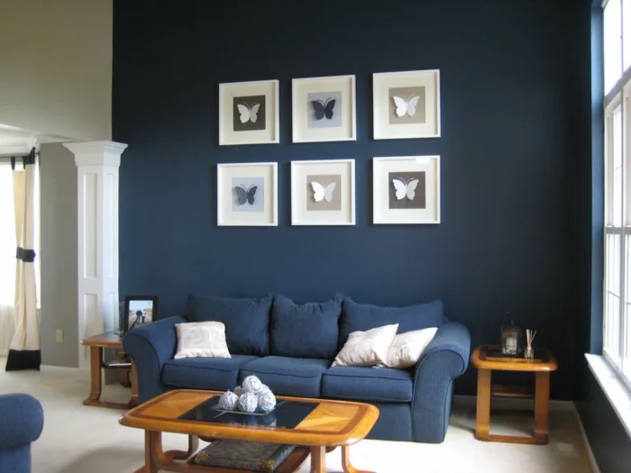 Sofa in einem dunklen Blauton und dunkelblaue Wand mit Wandbildern