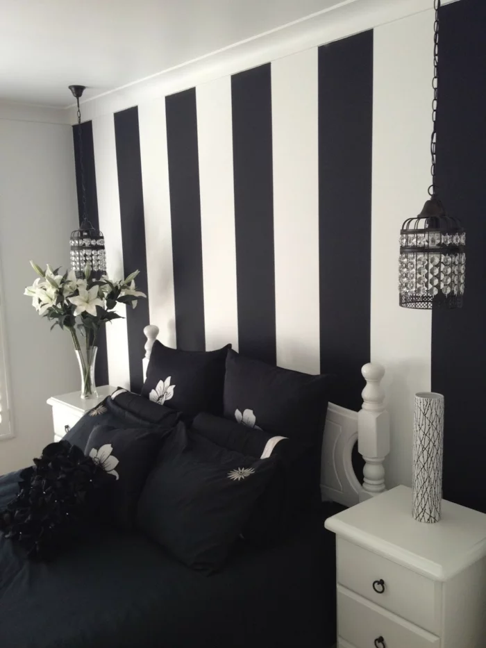 modernes Schlafzimmer mit schwarzer Bettwäsche und gestreifter Wandtapete