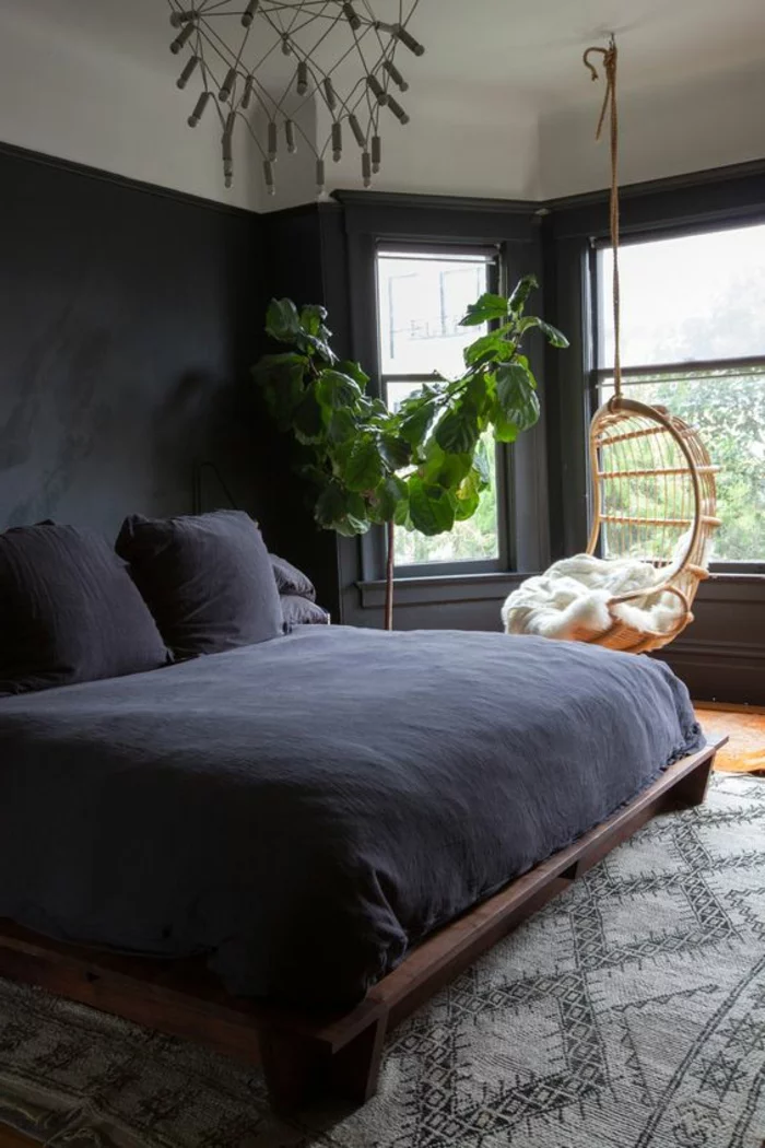 schwarzes Schlafzimmer mit Hängesessel, Topfpflanze und Leuchter