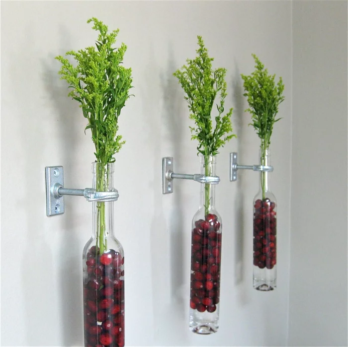 gläserne Flaschen mit Pflanzen, an der Wand befestigt
