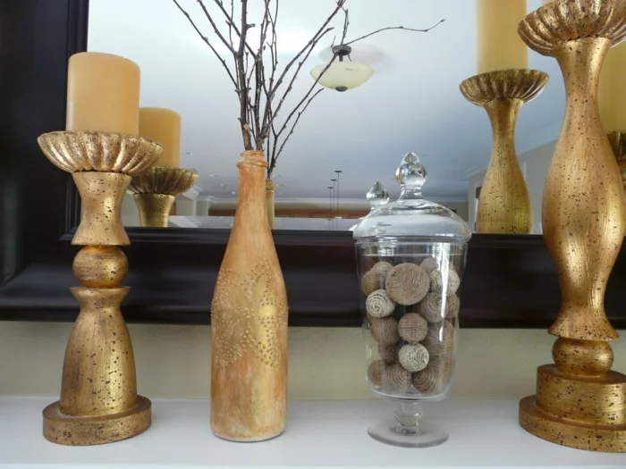 Deko Flaschen in Golden neben Kerzenhältern in goldener Farbe