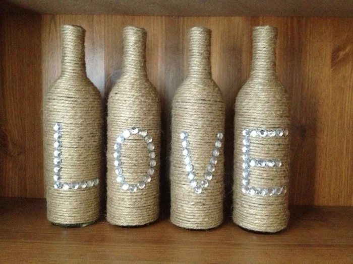 vier Flaschen, mit Schnur umwickelt, und mit Buchstaben dekoriert