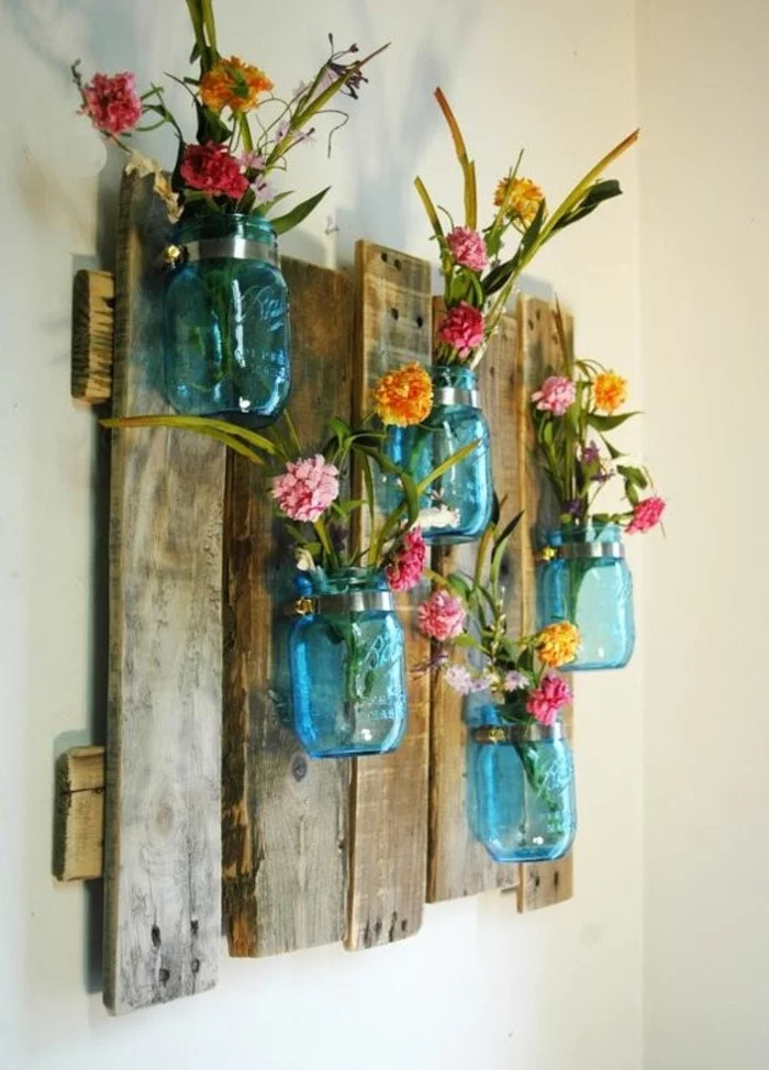 Holzplatten mit blauen Einmachgläsern mit Blumen