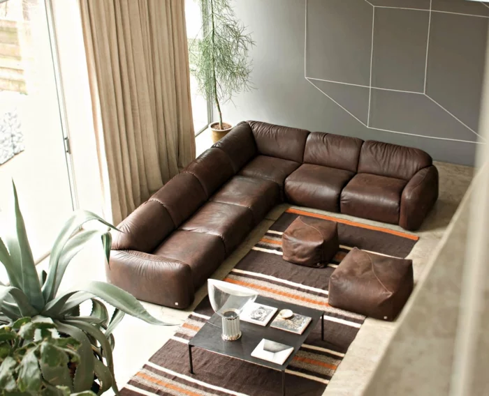 modernes Wohnzimmer mit braunem Sofa, langen Gardinen und Teppichläufer auf Streifen 