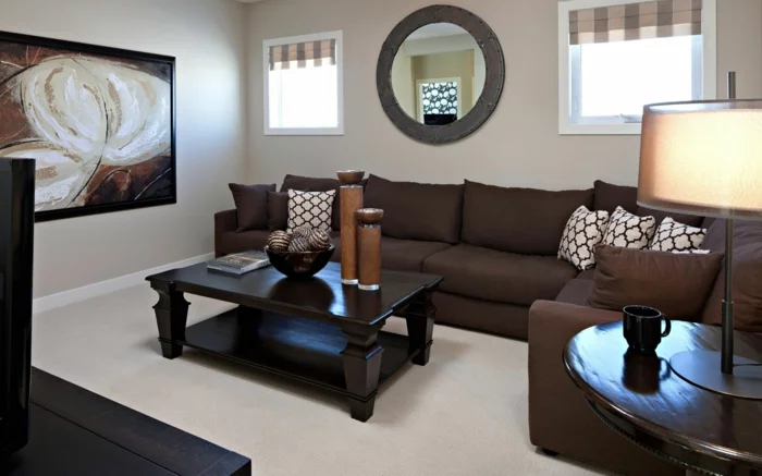 kleines Wohnzimmer mit dunkelbraunem Sofa, hellen Wänden und Wandspiegel