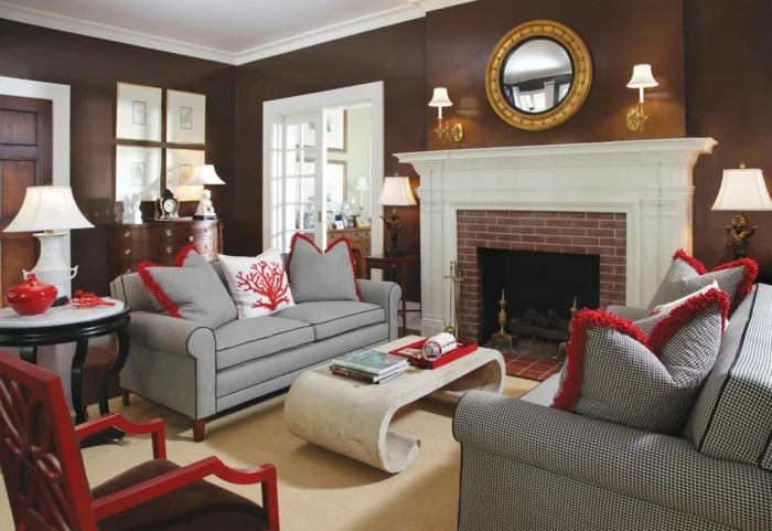 Wohnzimmer in Braun mit einem weißen Kaminsims, grauen Sofas und roten Akzenten