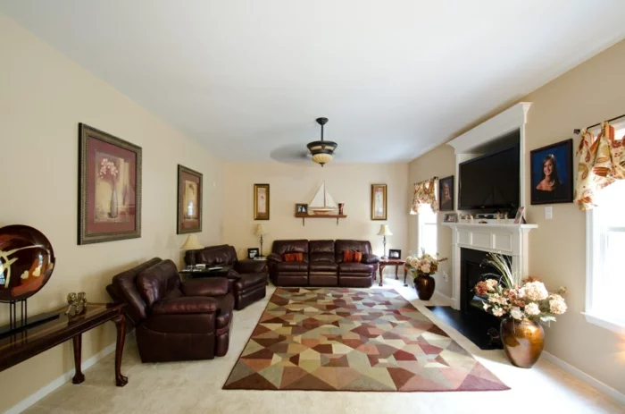 Wohnzimmer mit braunen Ledermöbeln, geometrischem Teppich und hellen Wänden