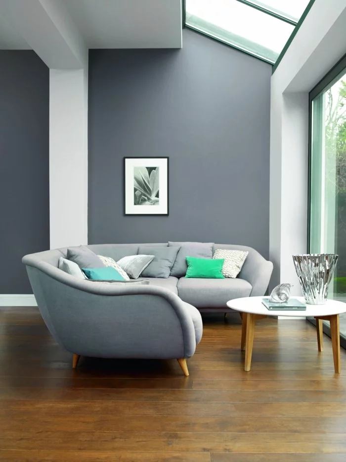 geräumiges Wohnzimmer gestalten mit modernem grauen Sofa und Holzboden