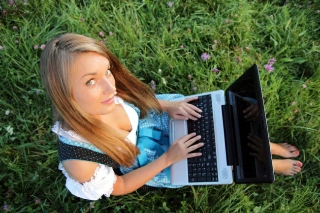 Dirndl in Blumenwiese mit Laptop von oben