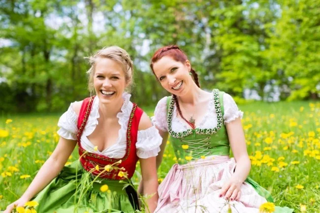 Young women in traditional Bavarian clothes - dirndl or tracht - on a meadow in spring