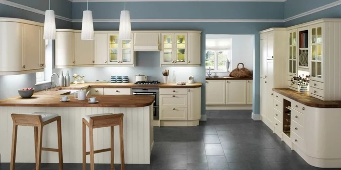 moderne Küche mit cremeferbenen Küchenschränken, grauen Wänden, Hängelampen und grauen Bodenfliesen 
