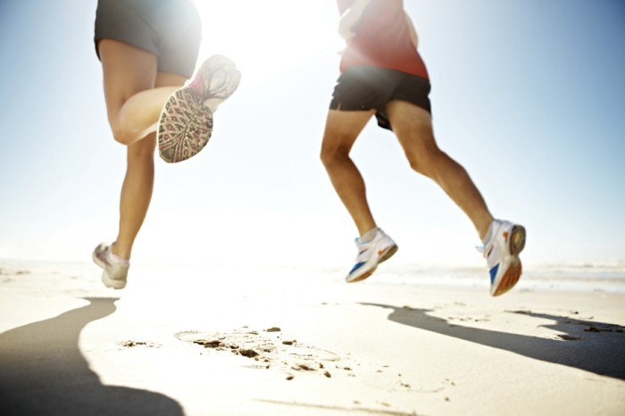 Cropped view of two runners jogging on the beach