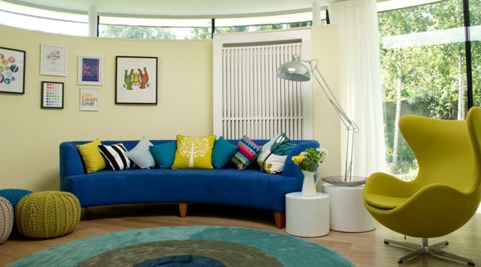teppich rund blaues sofa farbige dekokissen grüner sessel weiße beistelltische