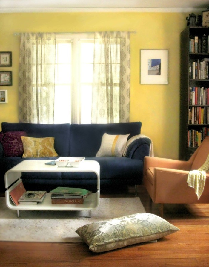 wohnungseinrichtung hellgelbe wandfarbe dunkles sofa weißer teppich