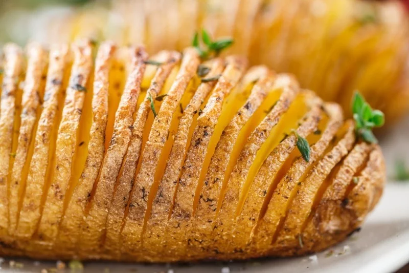Hasselback potatoes with herbs on a plate