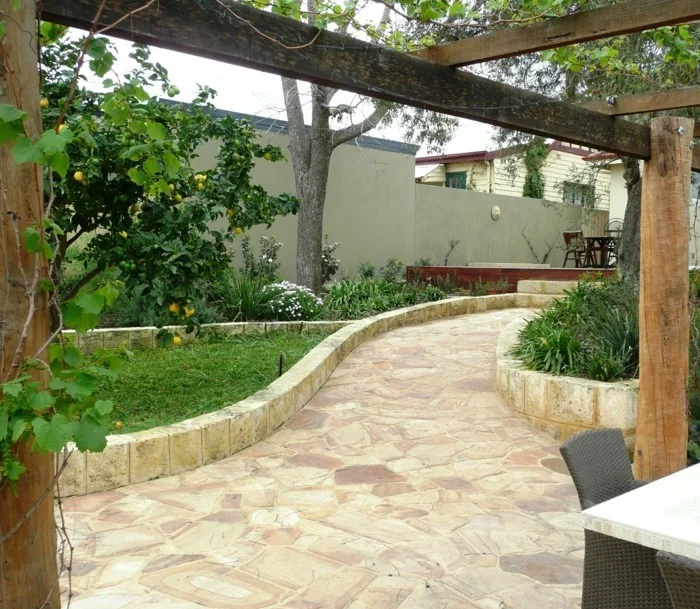 mediterrane Gartengestaltung mit stilvollen Beeteinfassungen, Steinboden und Pergola