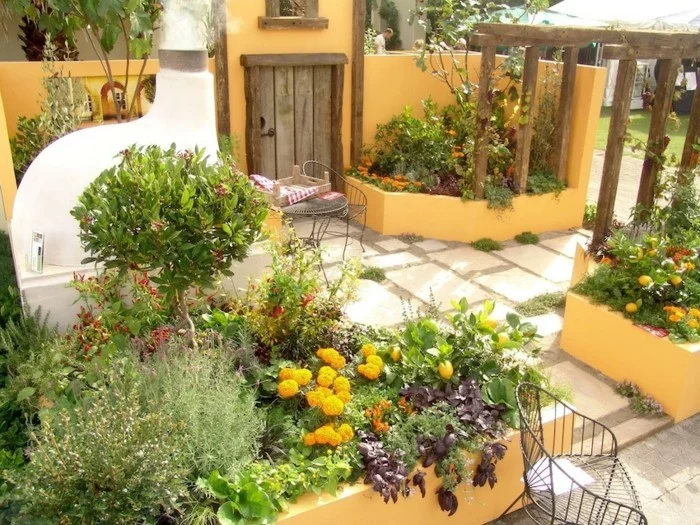 mediterrane Gartengestaltung mit Blumenbeeten in Orange und Metallmöbeln