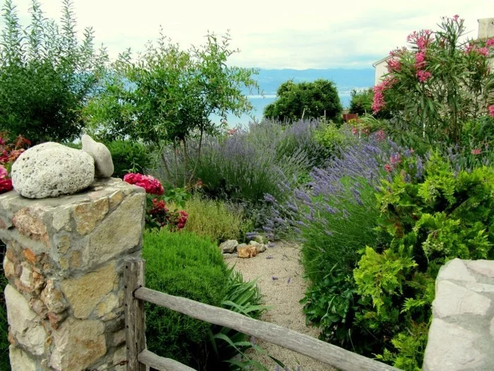 mediterraner Garten mit einem schönen Gartenzaun, Sand und Pflanzen