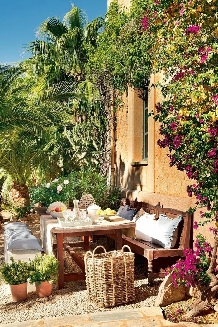 mediterraner Garten mit Gartentisch, Gartenbank und vielen Dekokissen
