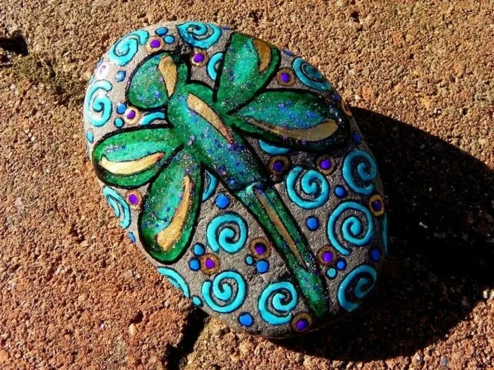eine bunte Libelle gemalt auf einem Stein 