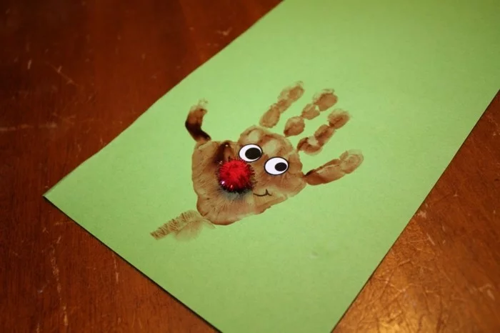 Rudolph aus Handabdruck auf einem grünen Blattpapier