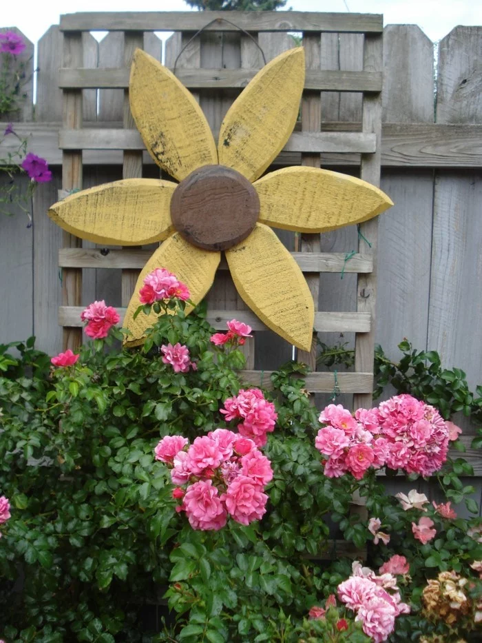 Gartendeko aus Holz als Blume gemacht und frische Blumenbeete 