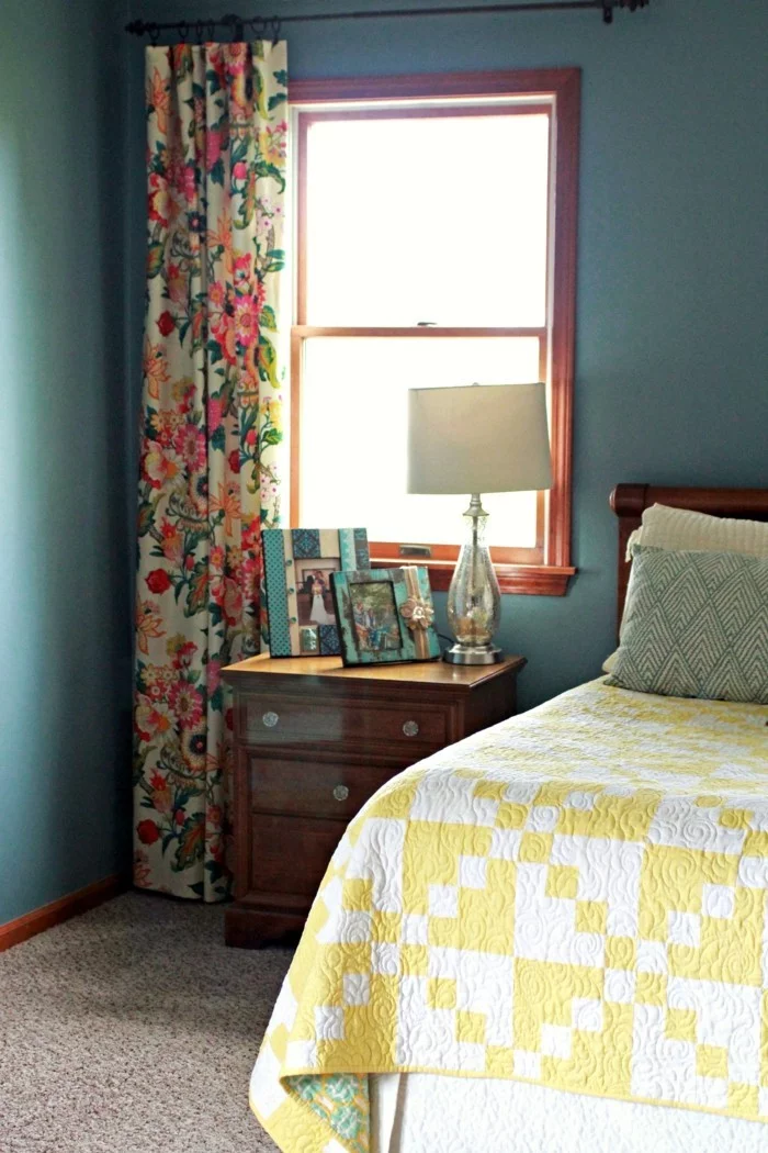 kleines Schlafzimmer mit grünen Wänden und farbigen Vorhängen auf Blumen