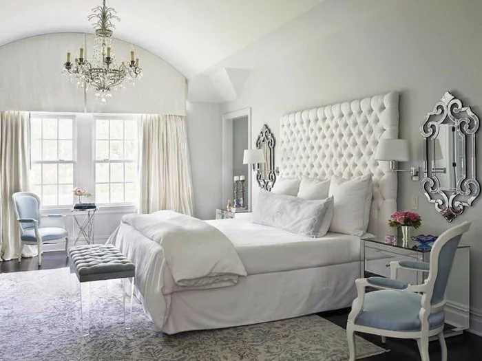 helle Gardinen, Kronleuchter, gemusterter Teppich und weißes Bett