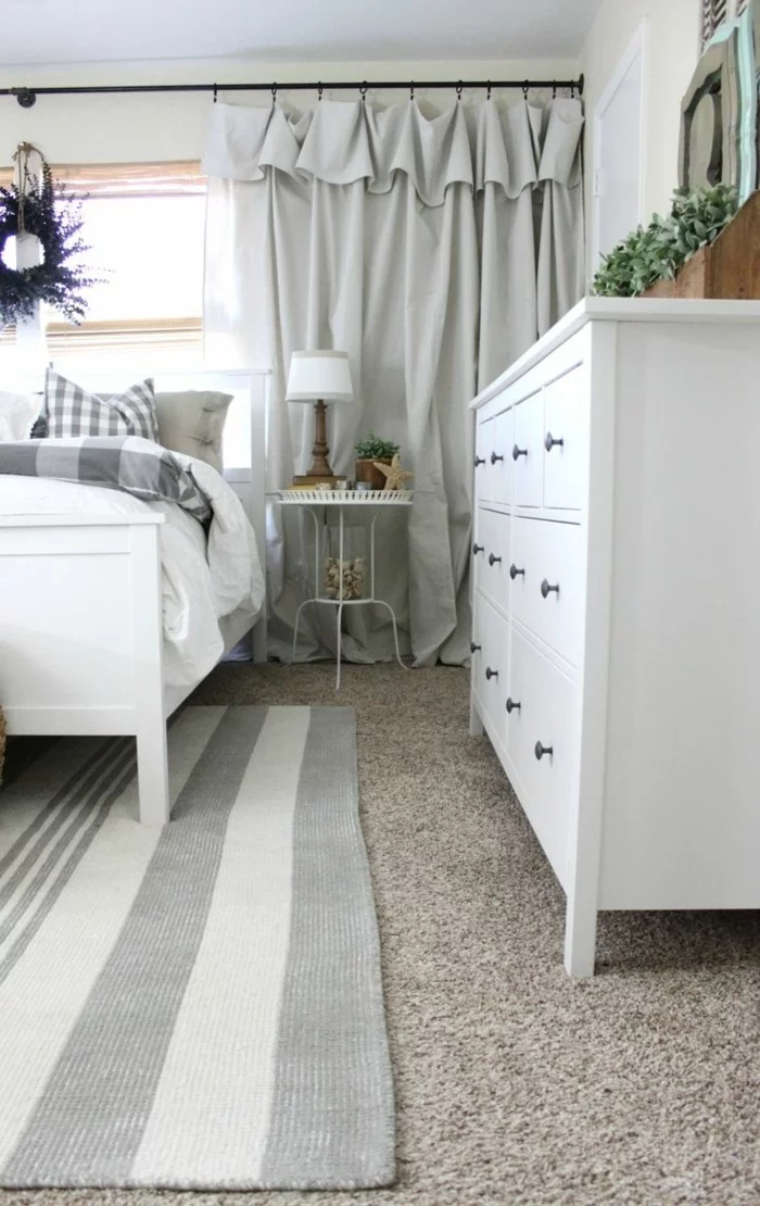Schlafzimmer Gardinen mit Draperie, Streifenteppich und weiße Möbel
