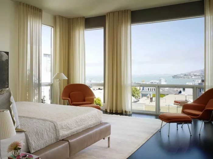 transparente Schlafzimmer Gardinen, weißer Teppich und orange Sessel 
