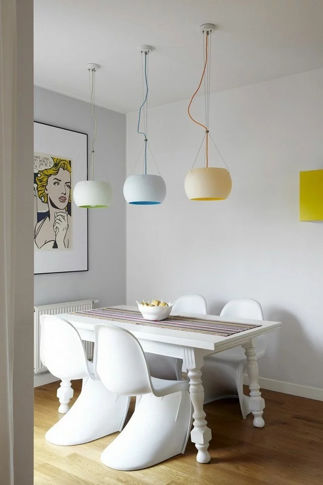 drei Esstisch Lampen in modernen Farben und weiße Möbelstücke