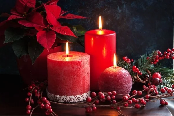 Weihnachtsstern neben brennenden roten Kerzen auf dem Tisch 