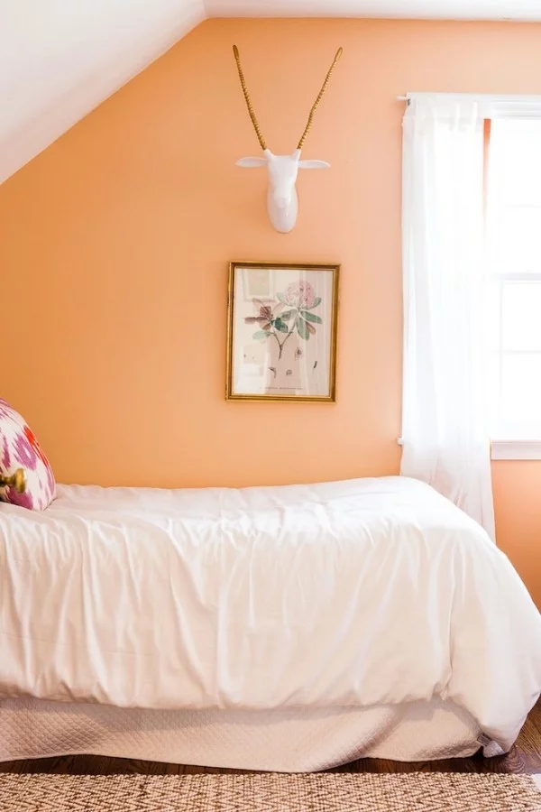 kleines Schlafzimmer mit Wandfarbe Apricot und weißer Bettwäsche