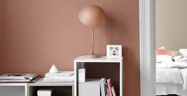 Wände mit Aprikosenfarbe, weiße Möbel und moderne Tischleuchte