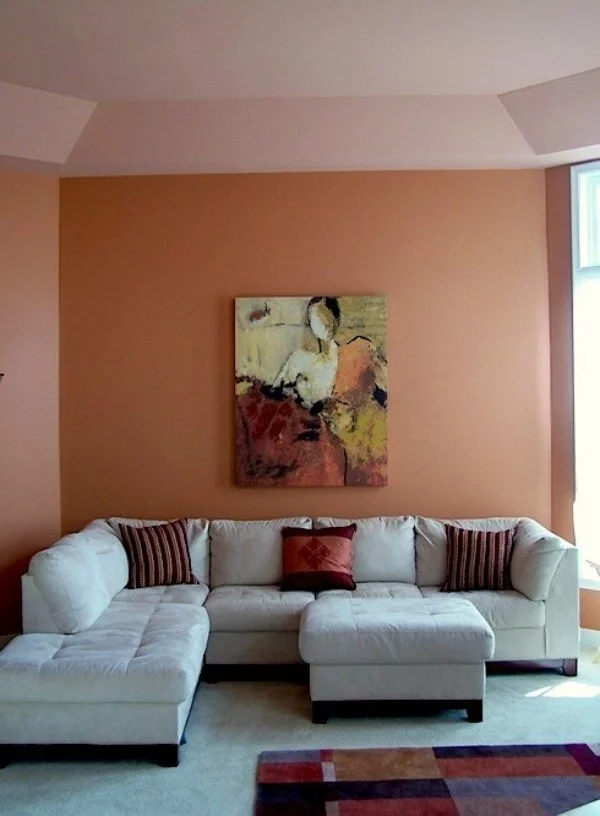 kleines Wohnzimmer mit weißem Ecksofa und Wandfarbe Apricot