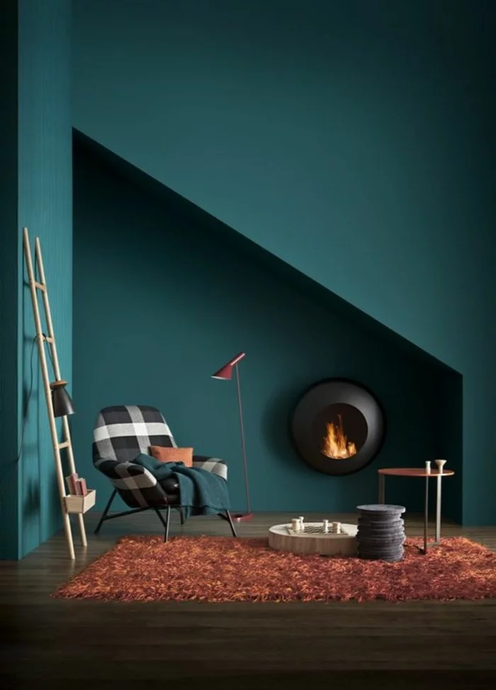 moderne Leseecke mit orangem Teppich, Feuerstelle an der Wand und Wandfarbe Petrol