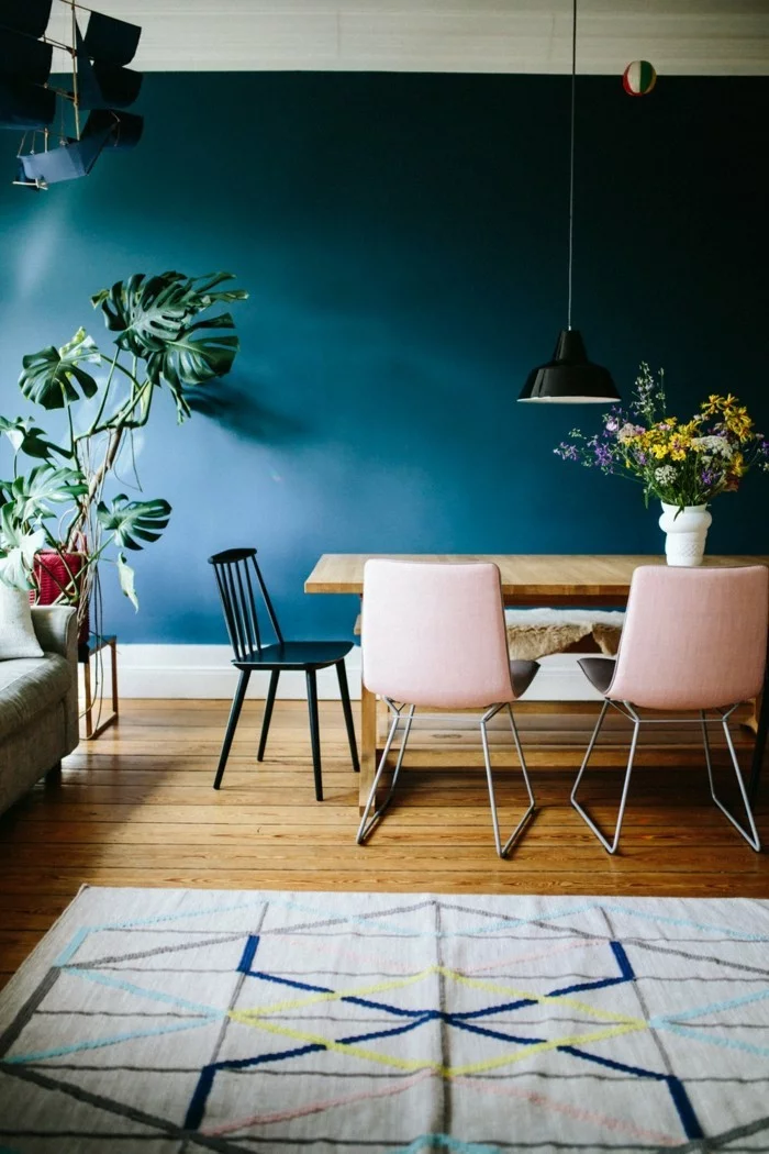 Essbereich mit hölzernem Esstisch, Stühlen in Pastellrosa und Wandfarbe Petrol