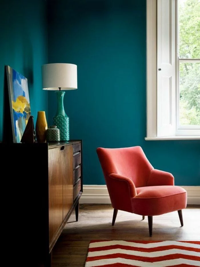Erholungsbereich mit orangem Sessel und Wandfarbe Petrol