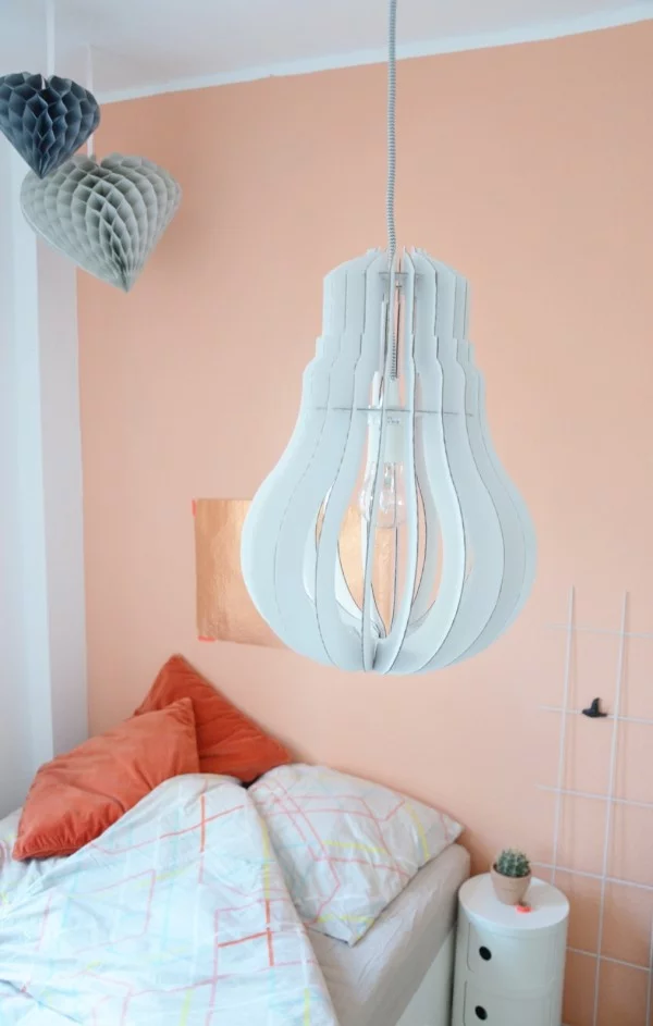 Schlafzimmer mit Hängeleuchte wie eine Birne, Origami-Hängedeko und Wandfarbe Apricot
