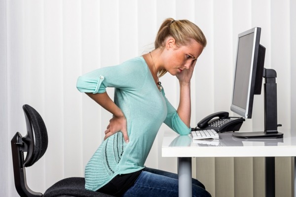 was hilft gegen rückenschmerzen junge Frau im Büro 