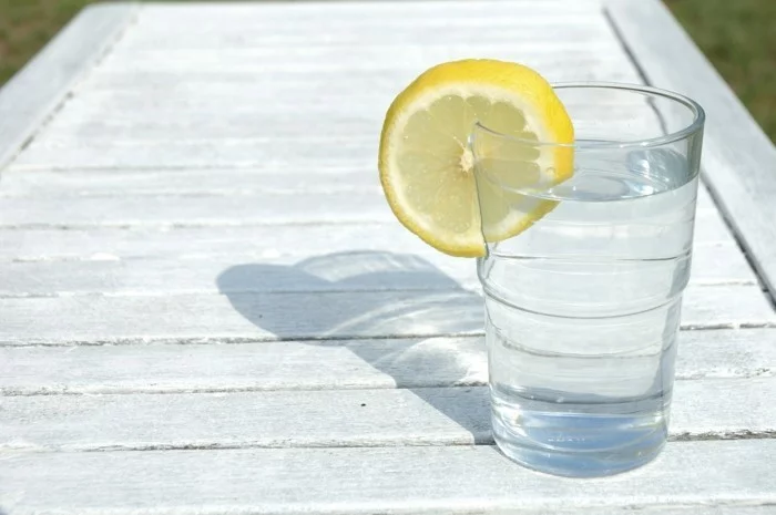 Detox Zitronenwasser im Glas auf weißem Tisch 