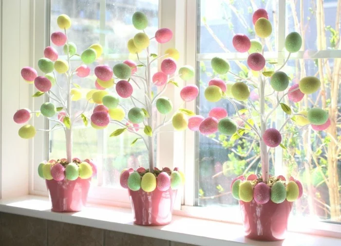 Fensterdeko Ostern mit Bäumen im Topf dekoriert mit bunten Ostereiern