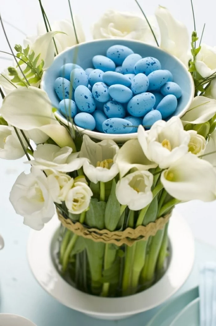 Blumenstrauß von Tulpen und Schale mit kleinen blauen Ostereiern in der Mitte