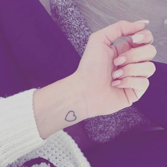 Mikro Herz-Tattoo am Handgelenk einer Frau 